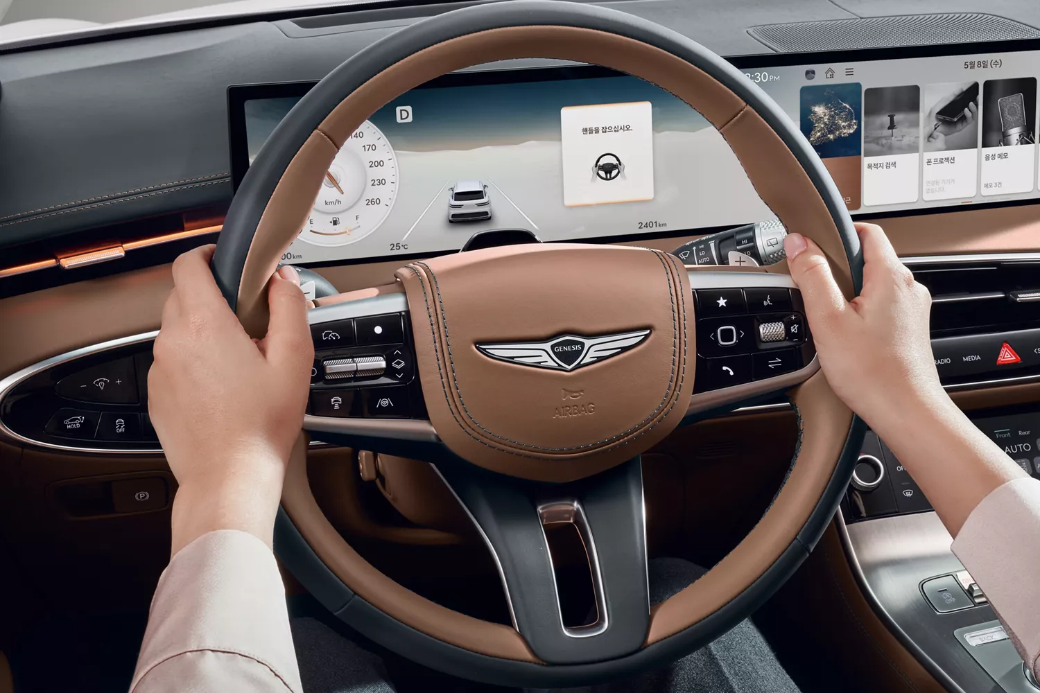 Hands on a two-tone steering wheel, with digital dashboard showing navigation and media.