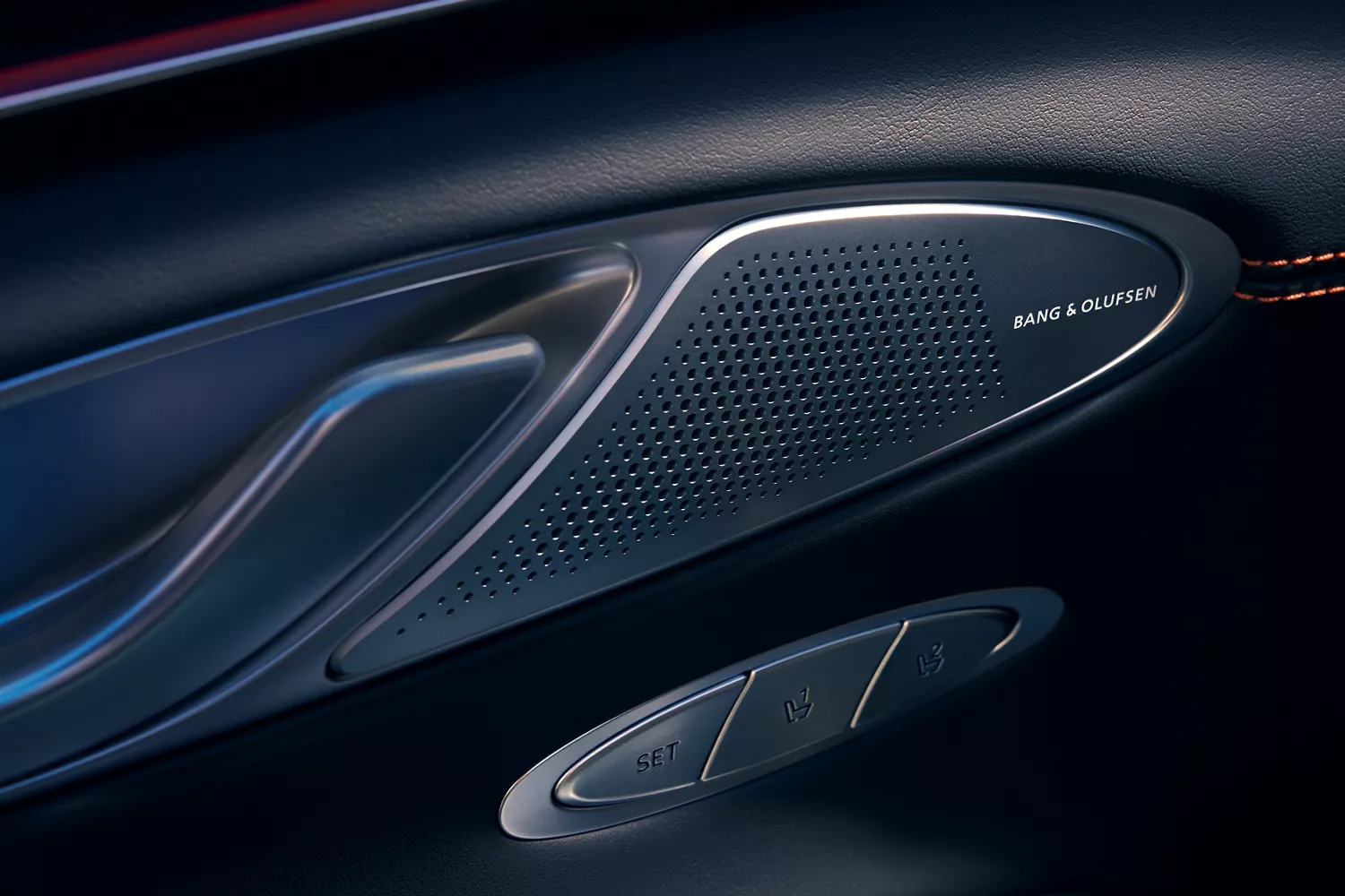 Close-up of a car's interior door panel, showing a Bang & Olufsen speaker, a door handle, and seat memory buttons.