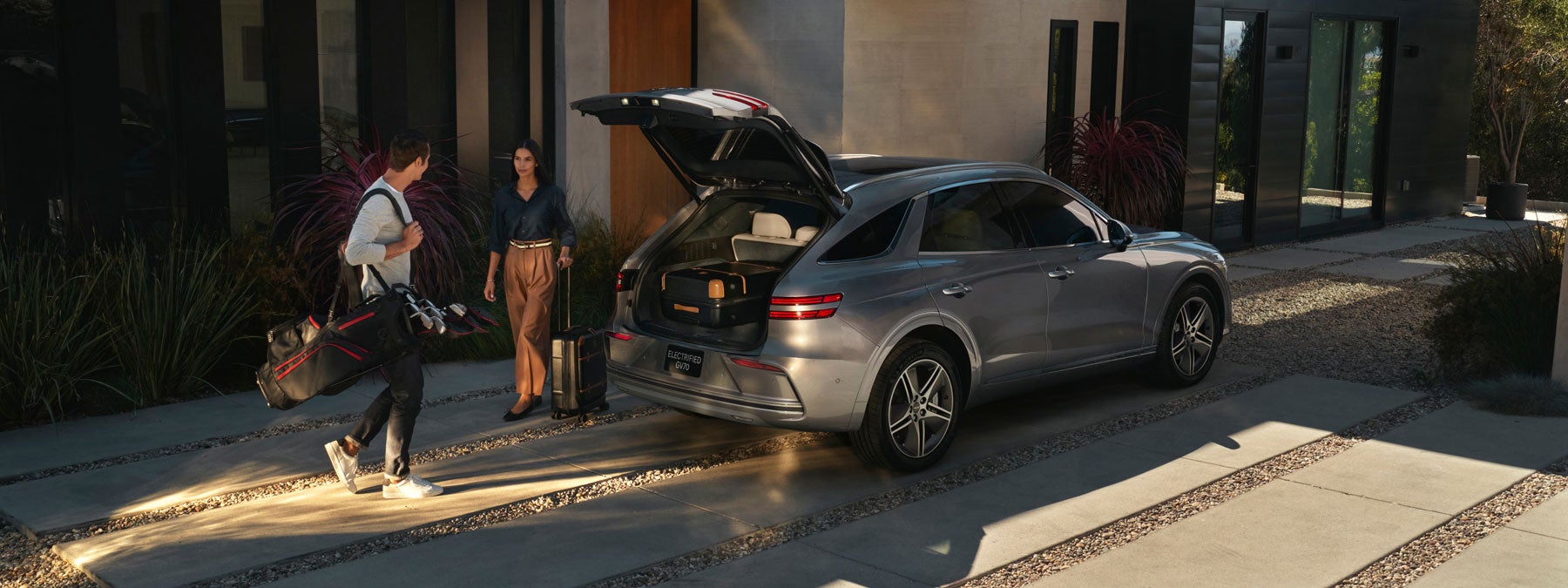Rear view of a Genesis GV70 SUV with the trunk open.