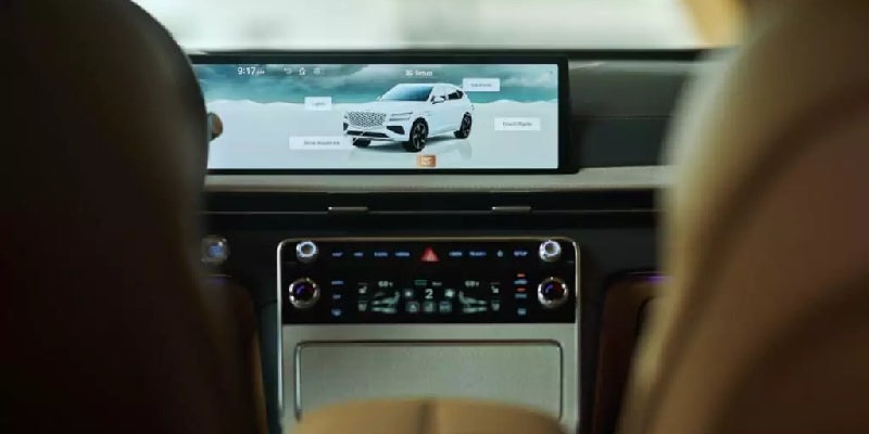 Interior view from the backseat of a car, showing the car's digital display with a white SUV on screen.